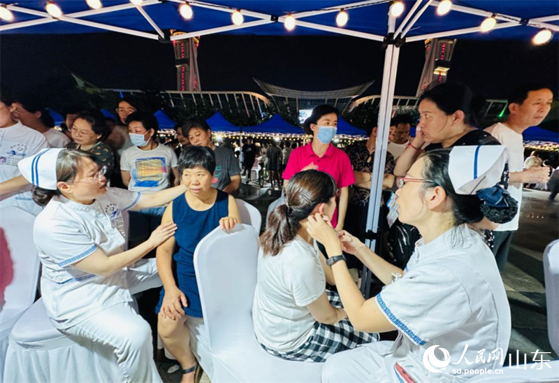濰坊市民在中醫(yī)藥文化夜市上體驗耳穴埋豆。人民網 喬姝攝