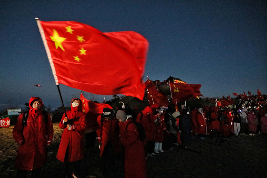 游客手舉五星紅旗等待日出。陳陽 攝