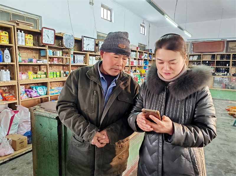 圖為王素蕓幫助老鄉(xiāng)調(diào)試手機(jī)設(shè)置