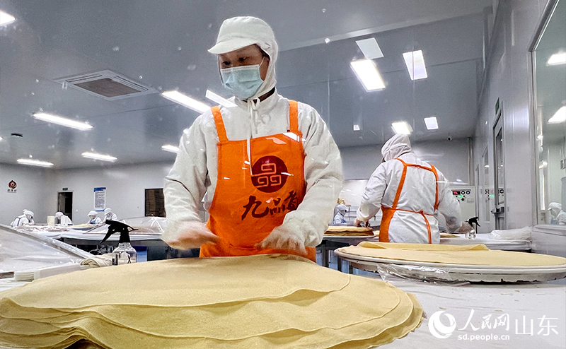 工人們手法嫻熟地將新鮮出鏊的煎餅層層疊起。人民網(wǎng)記者 劉祺攝