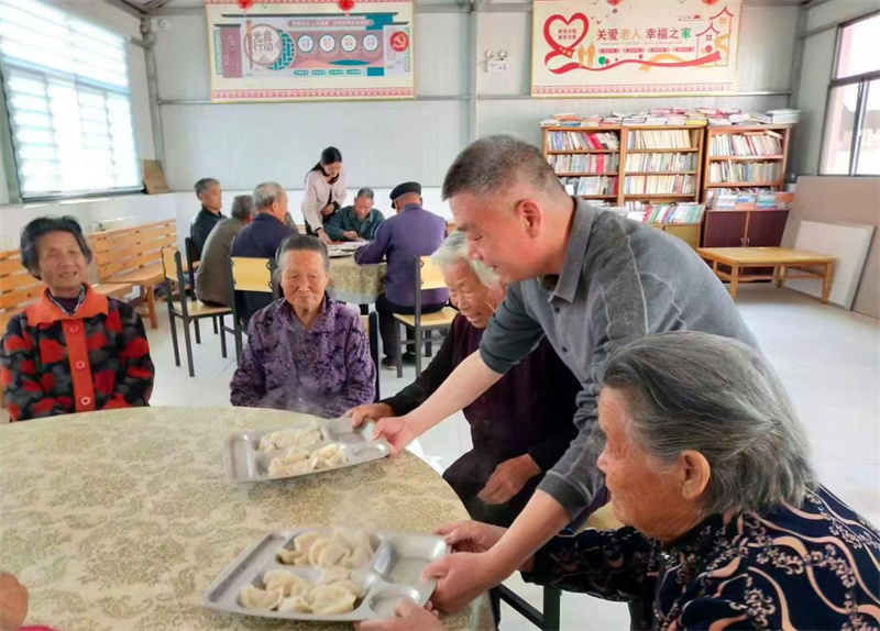 幸福院老人食堂里，李文新為老人端上熱騰騰的餃子。受訪者供圖
