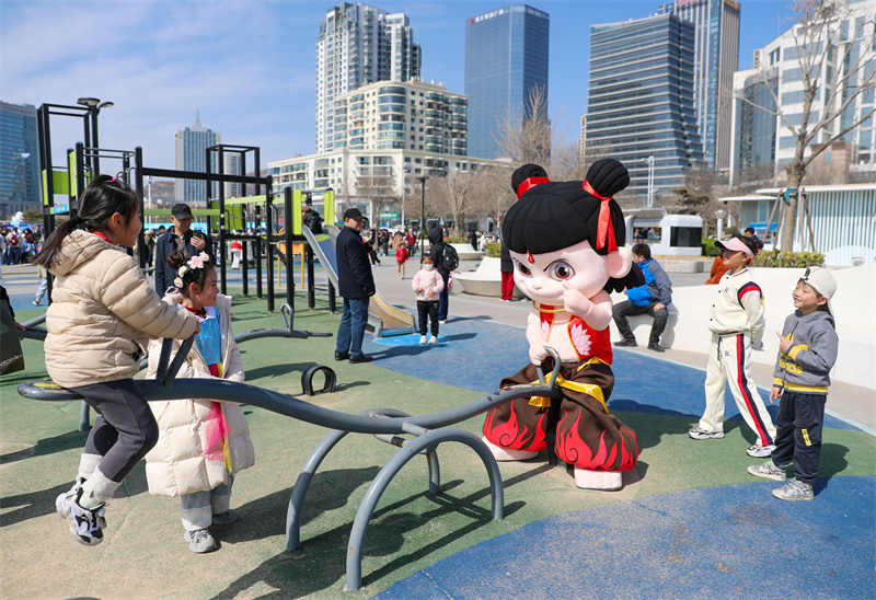 3月29日，在山東青島嶗山區(qū)石老人浴場，“哪吒”在和小朋友壓蹺蹺板。