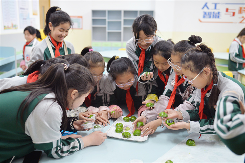 學生們在山東省青島市市北區(qū)普新小學開展的民俗迎清明活動上將做好的青團分類包裝。王海濱攝