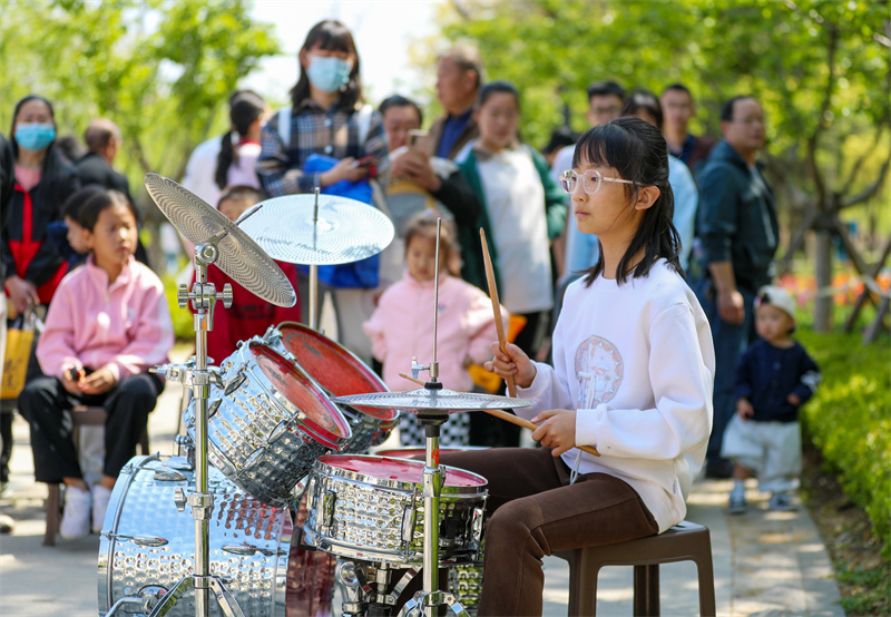 4月20日，一小朋友在山東青島萊西市月湖公園給游客表演架子鼓。張進剛攝