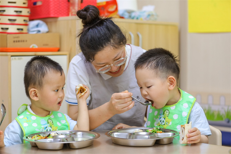 2025年5月14日，在山東省青島市李滄區(qū)職工子女愛心托育中心，老師教小朋友學(xué)吃飯。張鷹 攝 