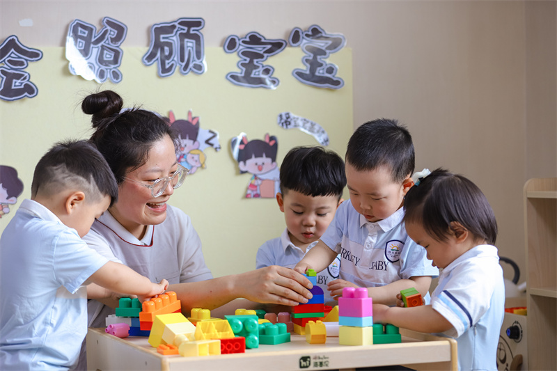 2025年5月14日，在山東省青島市李滄區(qū)職工子女愛心托育中心，小朋友在老師的精心照護下搭積木。張鷹 攝