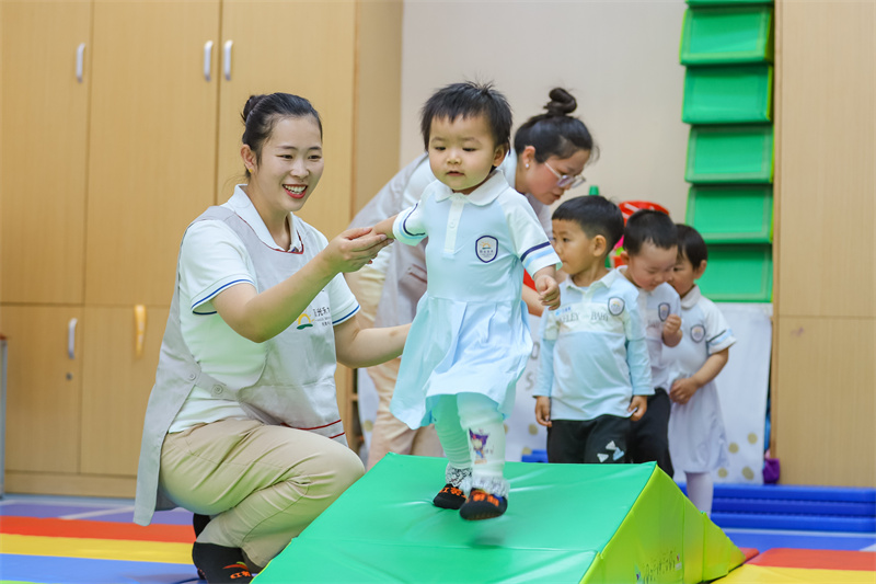 2025年5月14日，在山東省青島市李滄區(qū)職工子女愛心托育中心，小朋友在老師的精心照護下做運動。張鷹 攝 