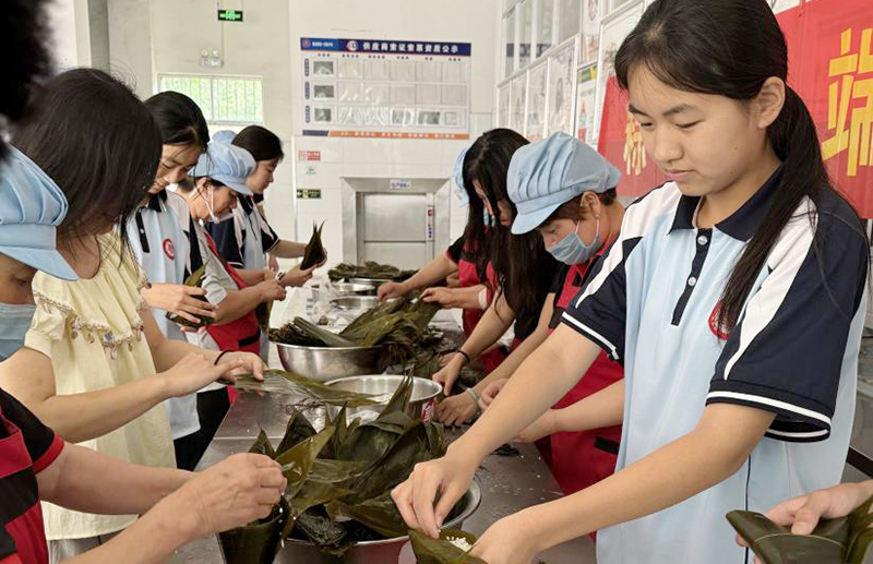 師生們圍在一起，體驗包粽子的樂趣。鄧璇攝