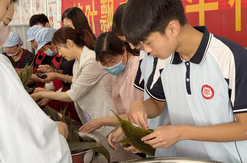 師生們圍在一起，體驗包粽子的樂趣。鄧璇攝